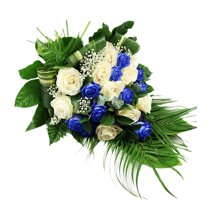 A luxurious teardrop-shaped funeral spray featuring blue and white roses is carefully styled against a clean white background, allowing its colours and shapes to speak without distraction. The eye is immediately drawn to the cluster of fully open roses that forms the centre of the design, packed closely together so their velvety petals almost overlap. Creamy white and ivory blooms alternate with rich sapphire blue roses, their tones arranged in a considered pattern that moves gently from one hue to the next, rather than in strict lines. This woven effect suggests unity and balance, a comforting sight for a family gathering at a memorial service in Stamford Hill or near the peaceful greenery of Springfield Park. Threaded among the roses are delicate stems of white baby's breath, each one tipped with clouds of tiny blossoms that lighten the arrangement and add a fine, lacy texture. Encircling the flowers is a structured bed of foliage, layered to create depth. Dark green, glossy leaves provide a strong backdrop, while bright green, feathery fern fronds fan out from the upper section, softening the outline and framing the blooms. From the lower right corner, elongated palm fronds stretch down and away, their narrow blades creating a calm, sweeping curve that defines the spray's cascading silhouette. Subtle sprigs of bluish-green, eucalyptus-like foliage introduce cooler notes and variation in leaf form, breaking up the green with a muted, silvery cast. Several broad leaves are expertly folded into crisp, banded shapes, striped in green and cream, then woven through the base, demonstrating a florist's practiced hand. The finished piece feels formal yet gentle, a composed tribute well suited for delivery across Stamford Hill to synagogues, churches, or funeral homes, offering a quiet message of peace, remembrance, and enduring love.